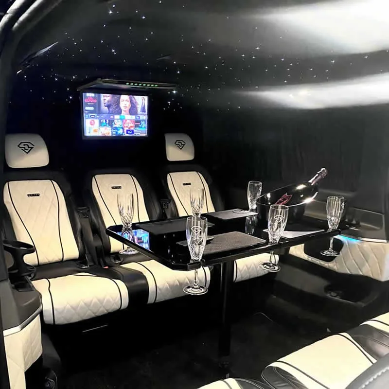Three quilted ivory and black seats behind a fold-out table set with crystal flutes and champagne on ice