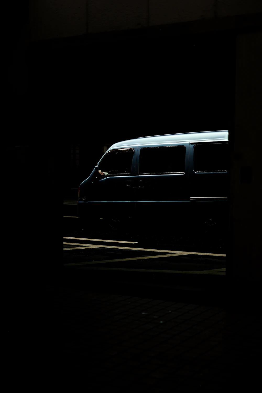 The outline of a dark van picked out by a single shaft of light